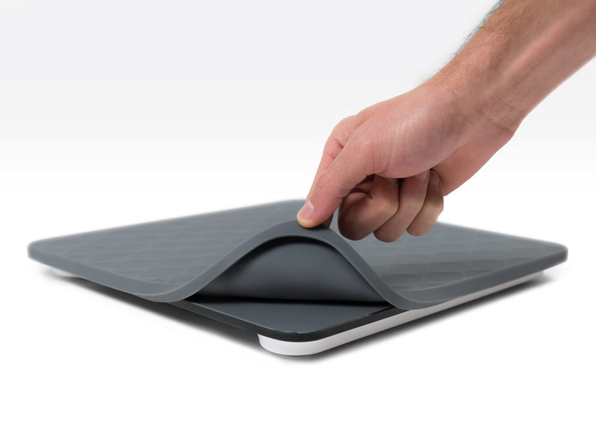 Gray scale with a removable silicone cover being held by a hand on a white surface.
