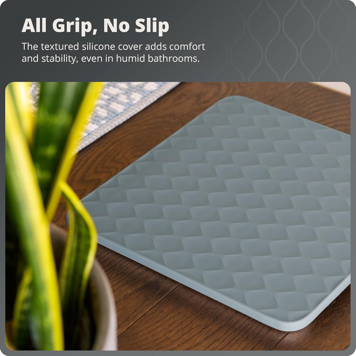 Textured silicone scale on a wooden surface with a plant and text that reads, "All Grip, No Slip: The textured silicone cover adds comfort and stability, even in humid bathrooms."
